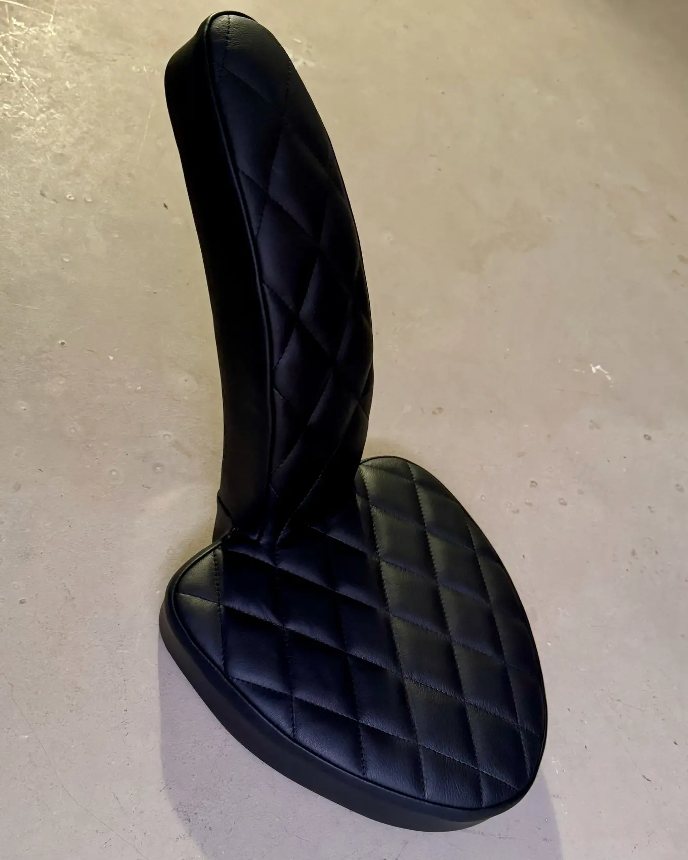 The upholstered seat, diamond stitched, standing on the floor