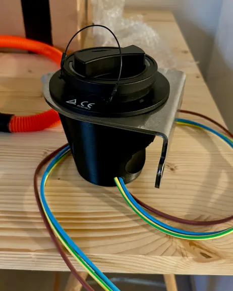 The charge port in its housing, wires attached, on the bench