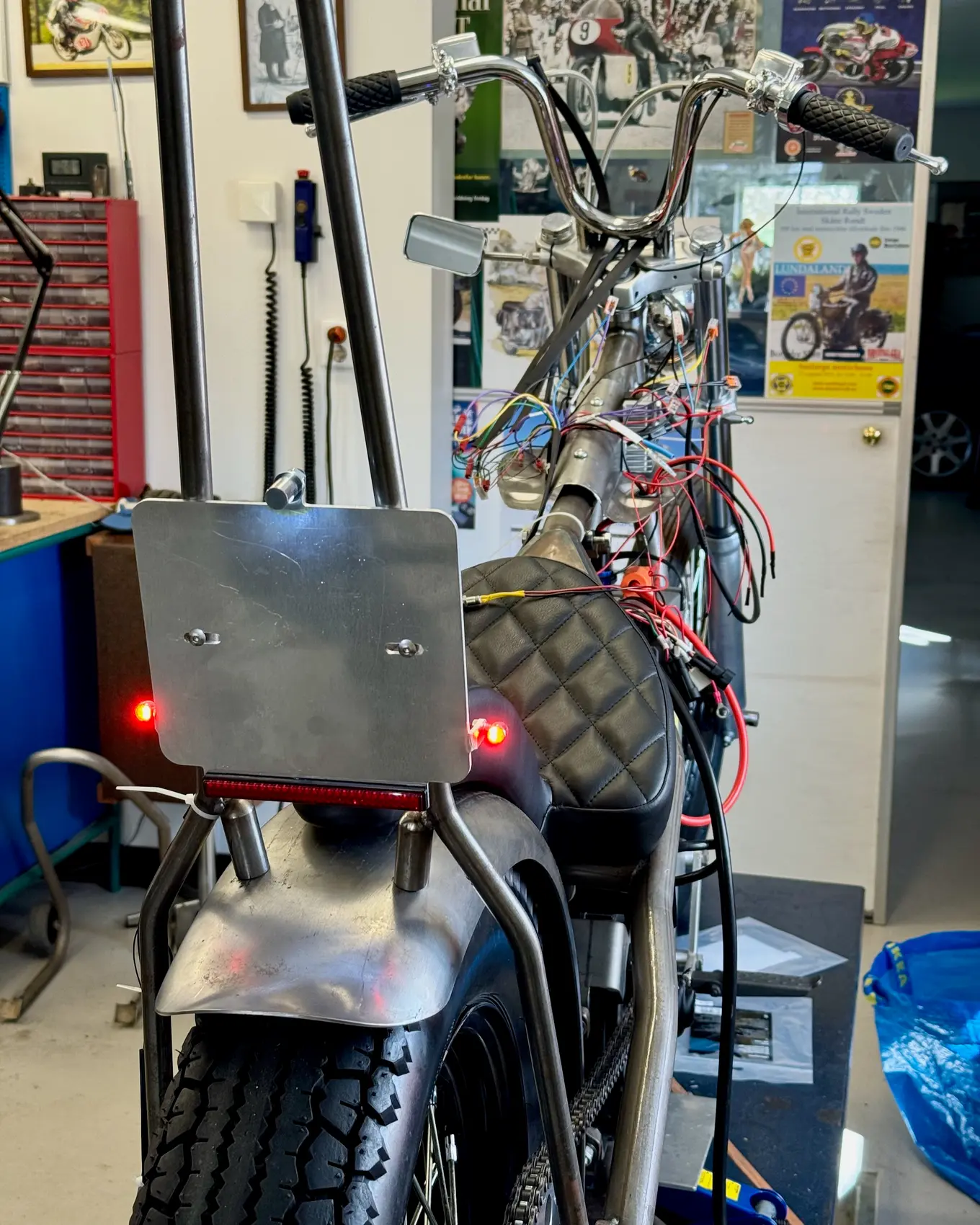 The rear of the bike in the garage with the taillight lit
