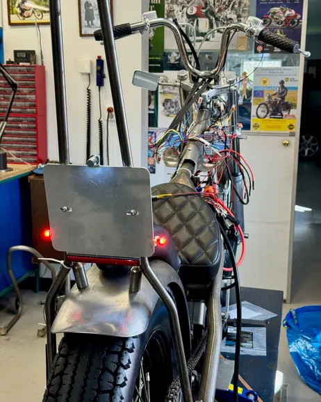 The rear of the bike in the garage with the taillight lit