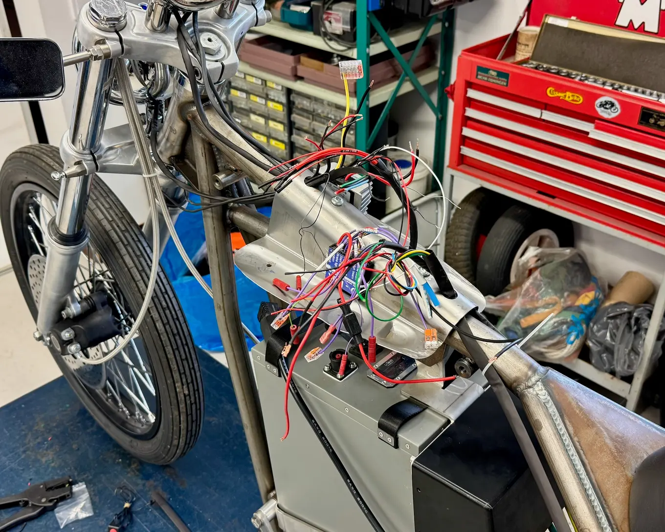 The bike on the lift with its wiring pulled out and laid over the frame