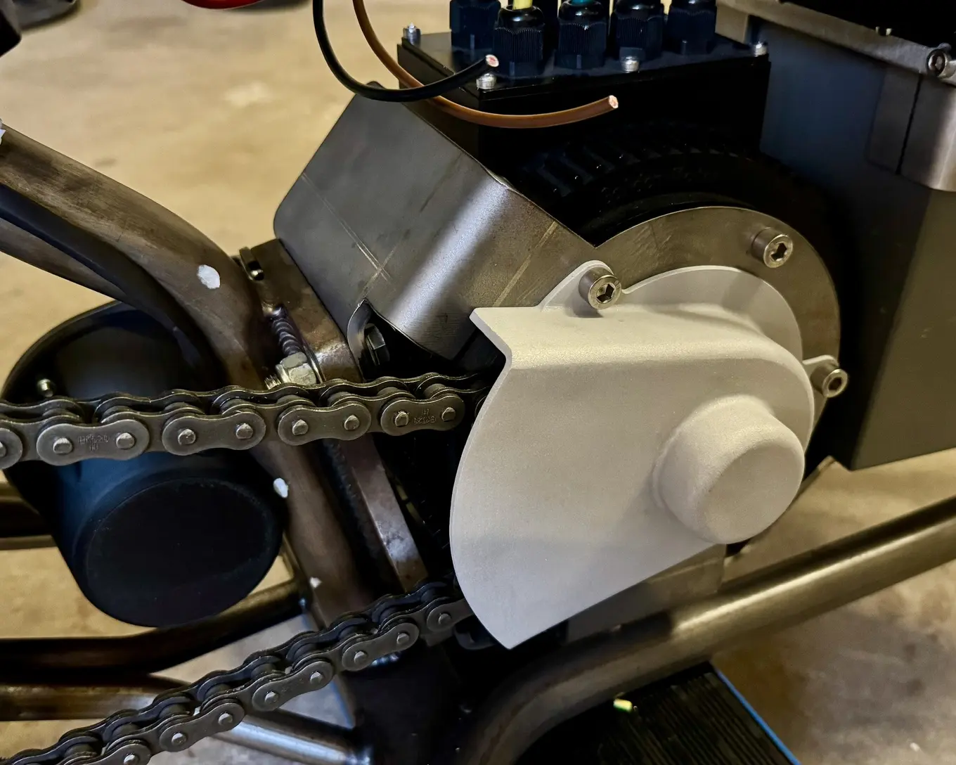 The updated front sprocket guard fitted over the drive, chain running below