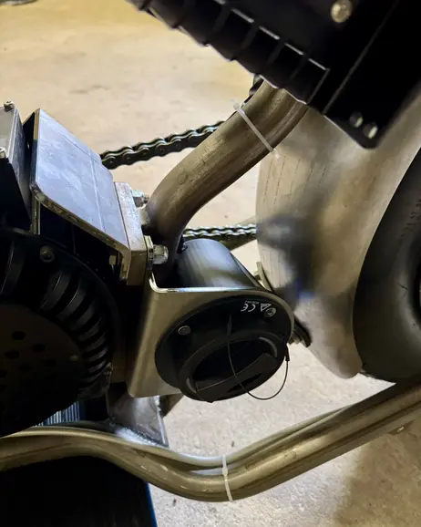 The charge port fitted in the frame, with the chain and motor behind it