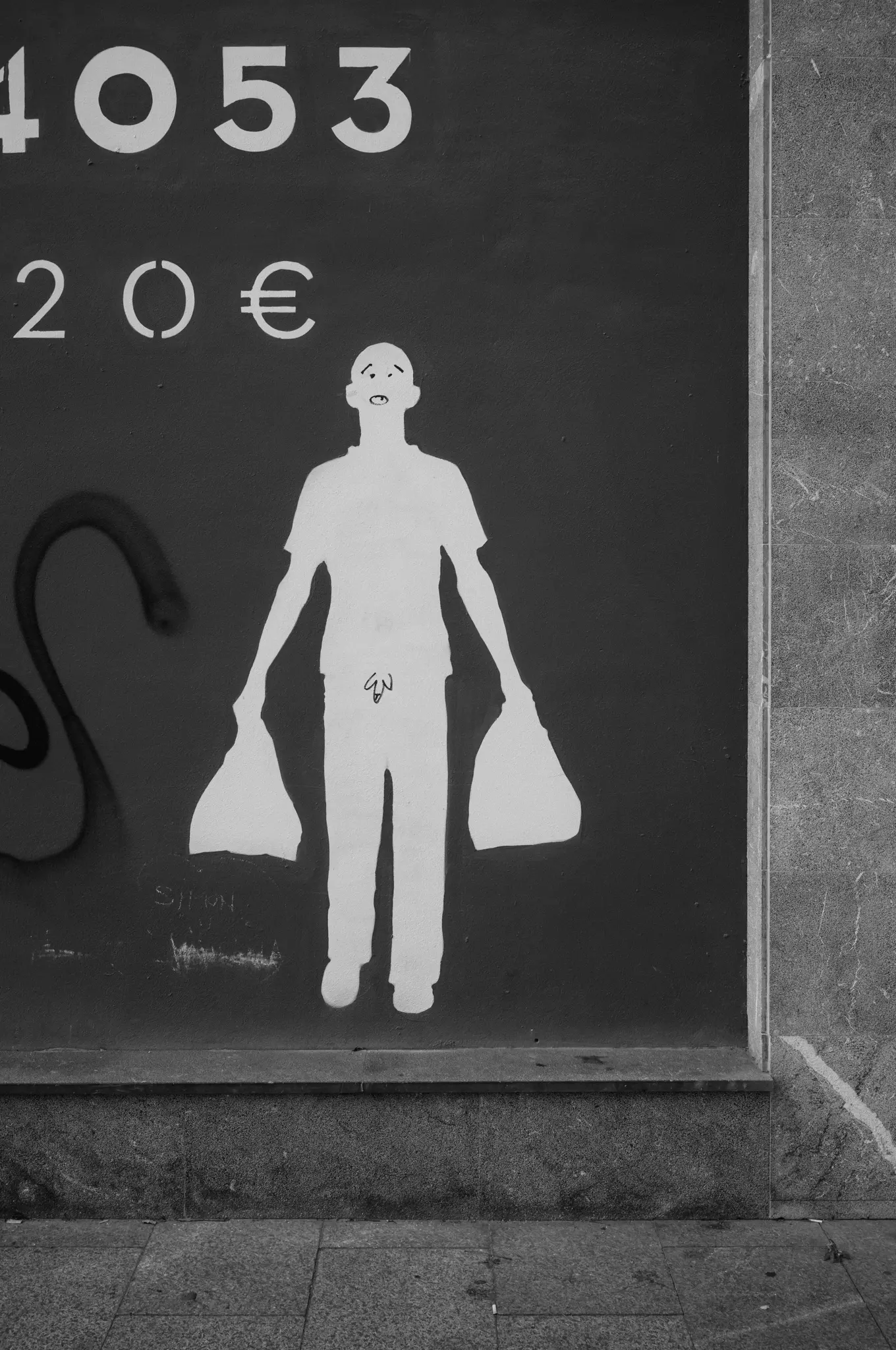 A white stencil of a figure carrying two shopping bags on a dark wall, a price painted above
