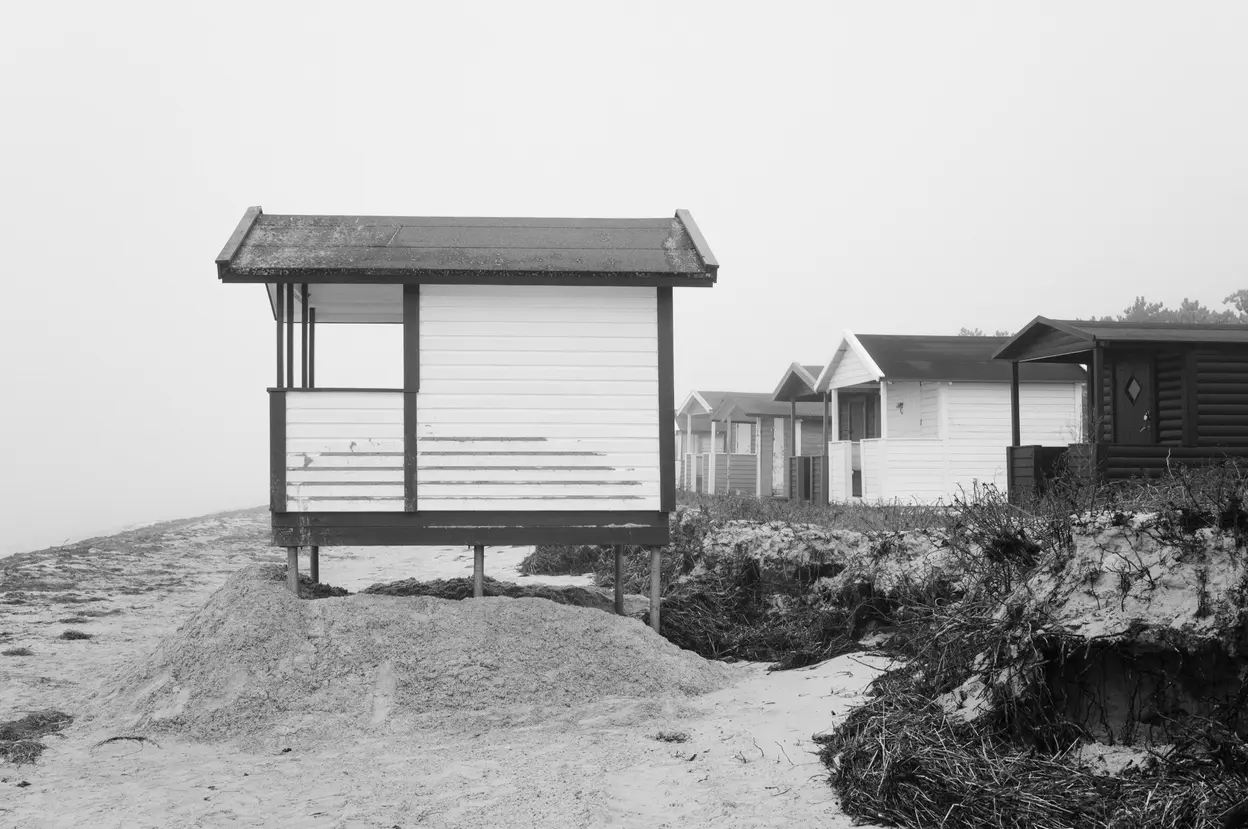 An open-sided hut standing on four posts at the edge of the sand