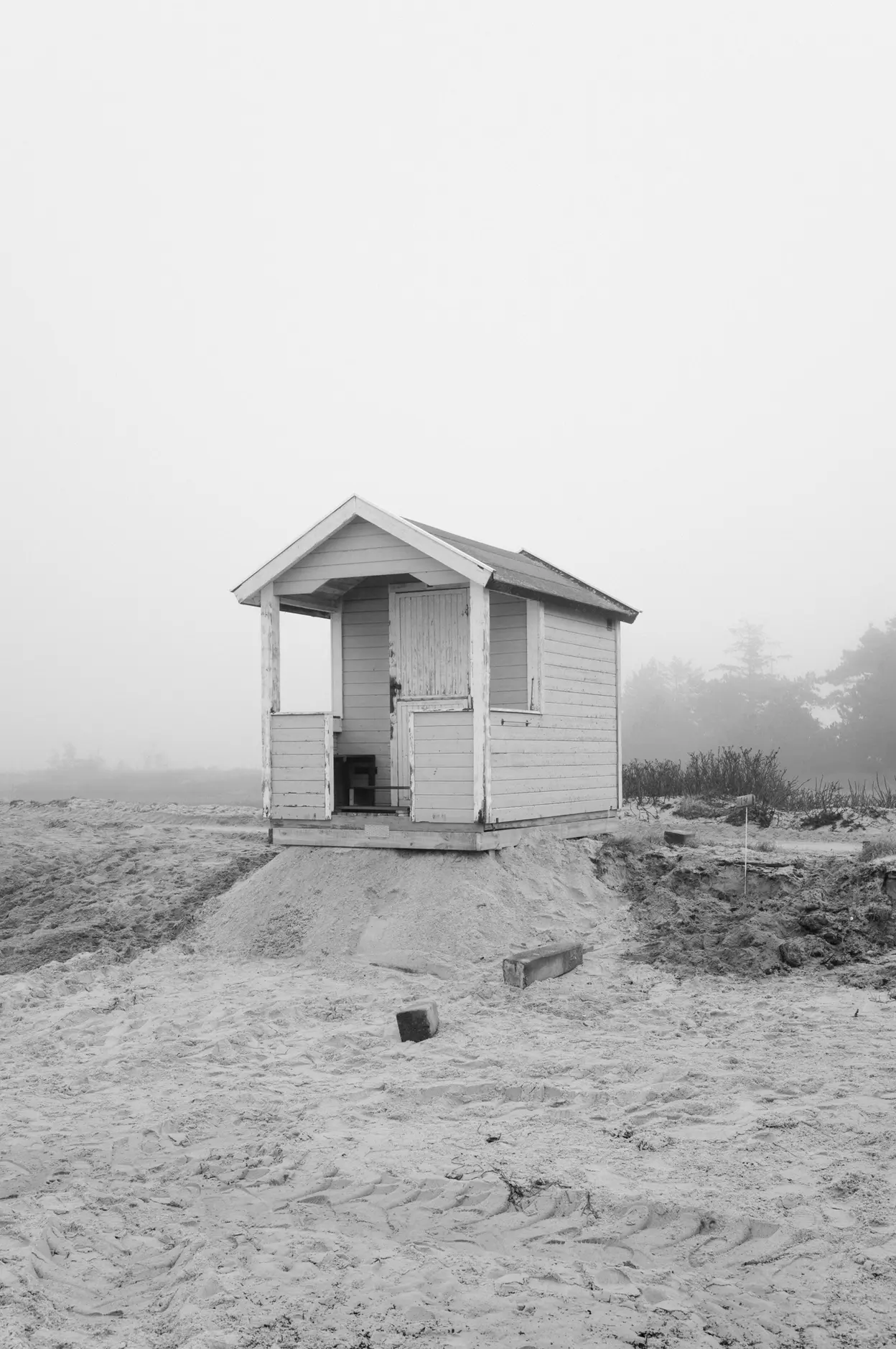 An open-fronted hut left standing on a mound of sand