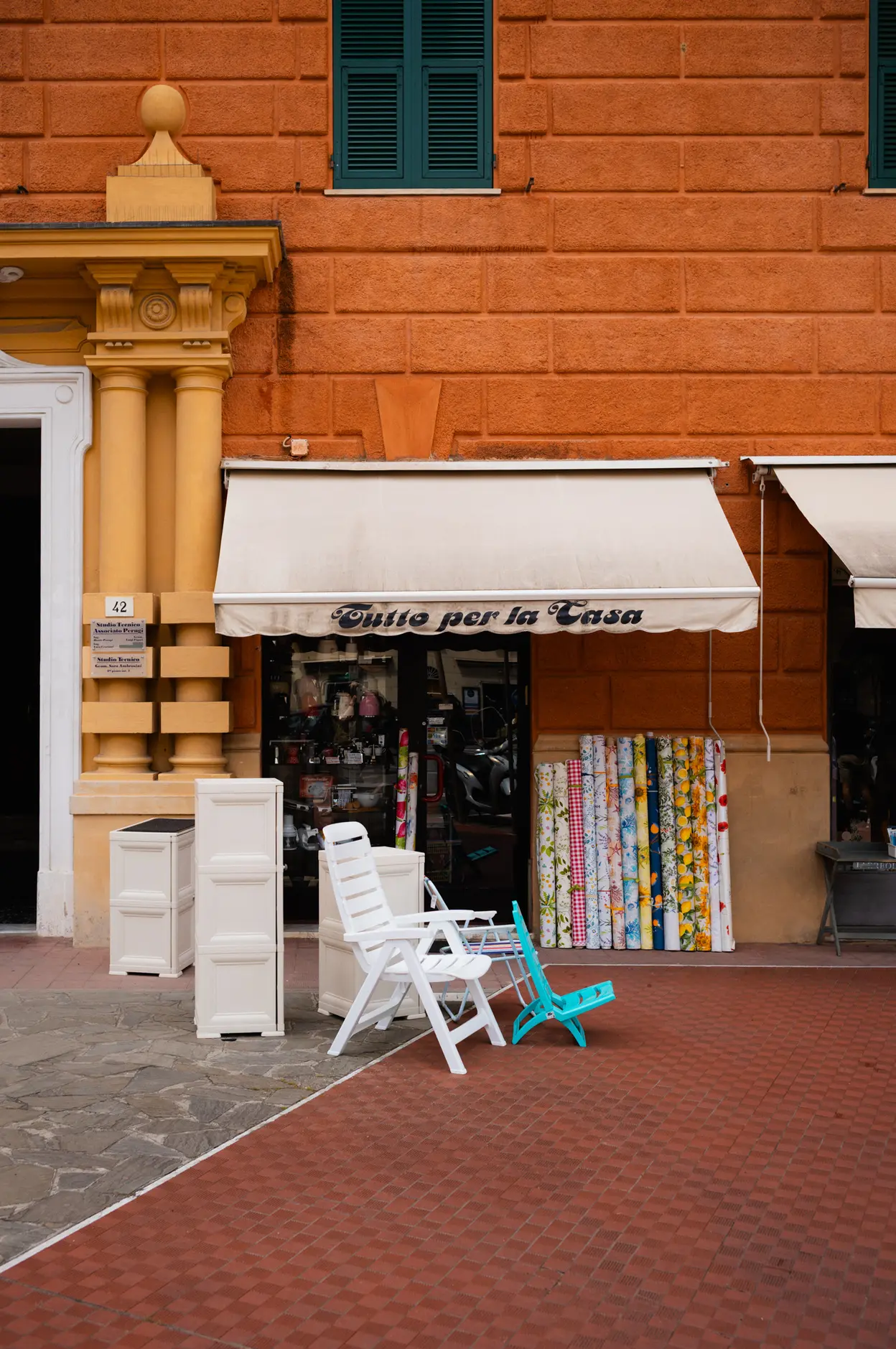Plastic chairs outside a shop, its awning lettered Tutto per la Casa