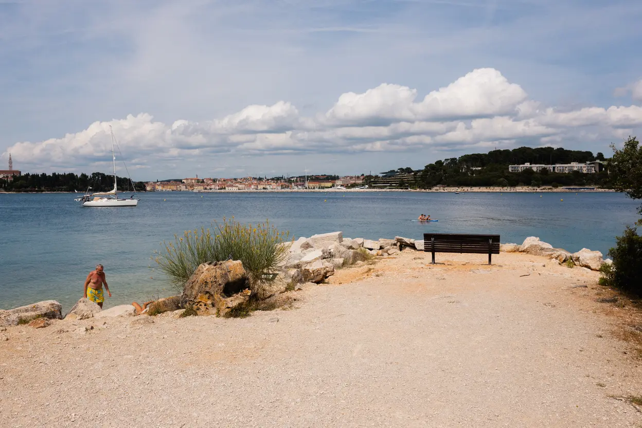 An empty bench at the end of a rock spit, the old town low on the far shore