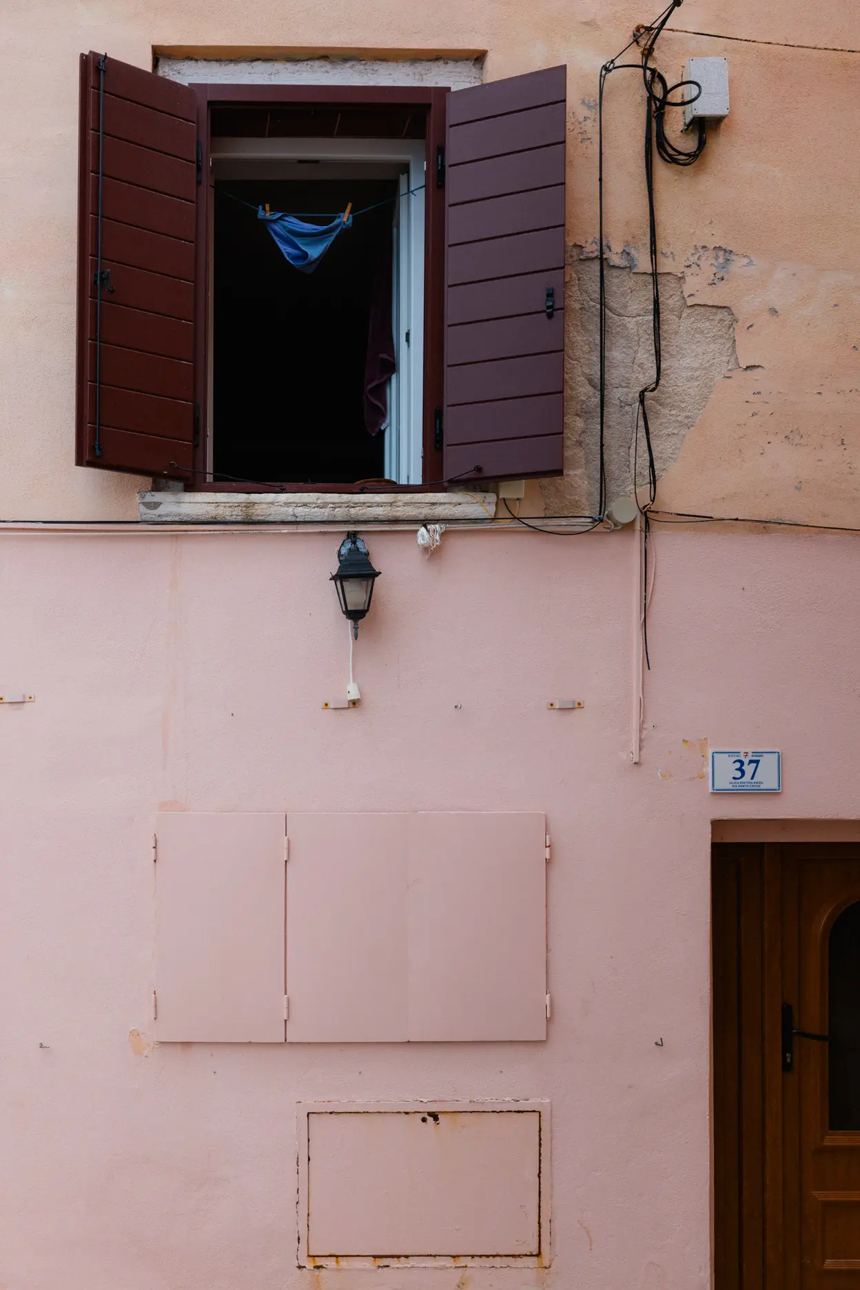 Swimming trunks hung to dry in an open window above a pink wall